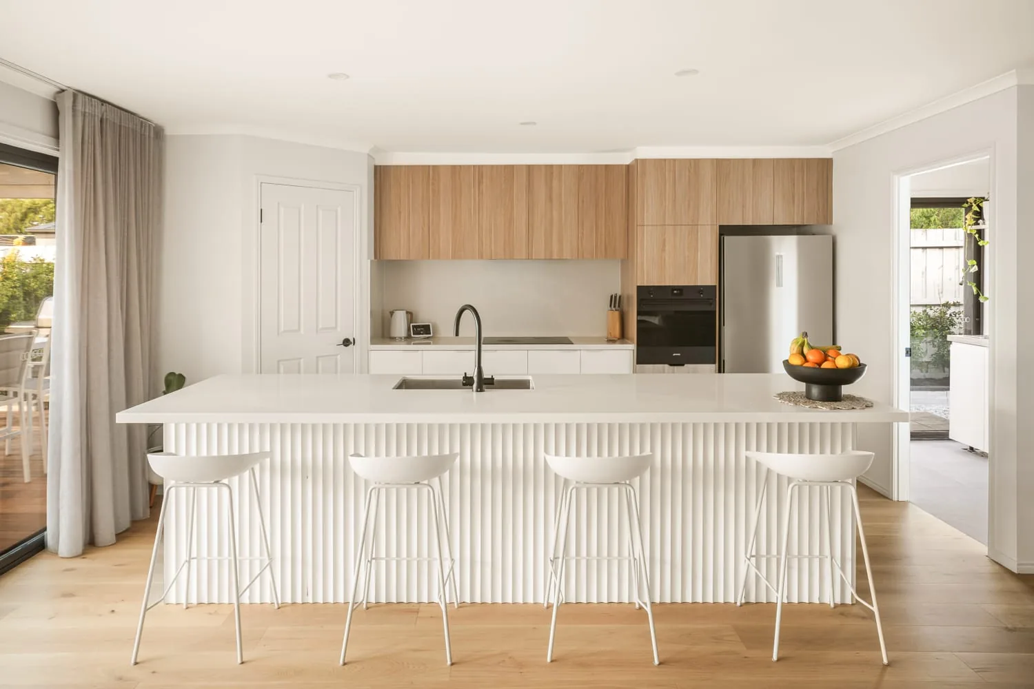 Kitchen with a stone island bench and timber joinery in a completed Combo Constructions renovation